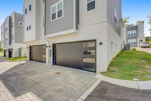 500 Creative Way Unit 16, Madison, TN 37115 - view of side of home featuring a garage, decorative driveway, central AC, and brick siding