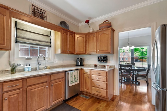 2710 Maylon Dr, Murfreesboro, TN 37128 - kitchen with stainless steel appliances, light wood finished floors, ornamental molding, a chandelier, and brown cabinetry