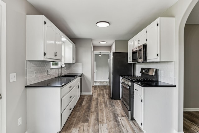 710 Krissy Ct, Columbia, TN 38401 - kitchen featuring appliances with stainless steel finishes, a sink, arched walkways, dark wood-style floors, and dark countertops