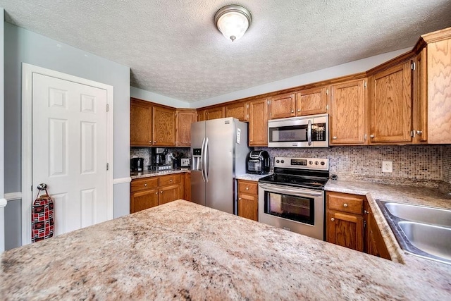 152 Cody Ct, Portland, TN 37148 - kitchen featuring stainless steel appliances, light countertops, brown cabinetry, a sink, and a textured ceiling