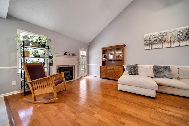 152 Cody Ct, Portland, TN 37148 - living room featuring high vaulted ceiling, light wood finished floors, a tile fireplace, and baseboards