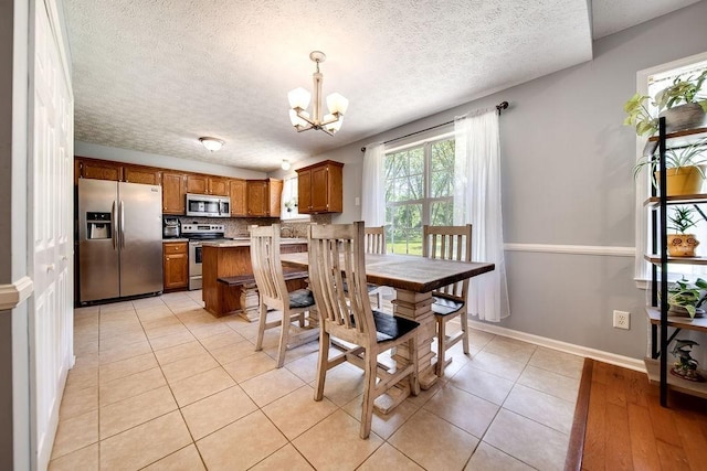 152 Cody Ct, Portland, TN 37148 - dining space with a chandelier, a textured ceiling, light tile patterned floors, and baseboards