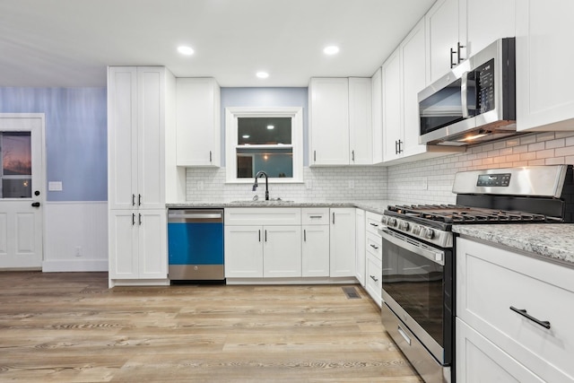 5430 Stacy Springs Rd, Springfield, TN 37172 - kitchen featuring appliances with stainless steel finishes, a sink, light wood-style flooring, white cabinetry, and light stone countertops