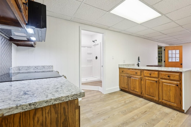 5430 Stacy Springs Rd, Springfield, TN 37172 - kitchen featuring light wood finished floors, a peninsula, brown cabinetry, black electric cooktop, and a sink