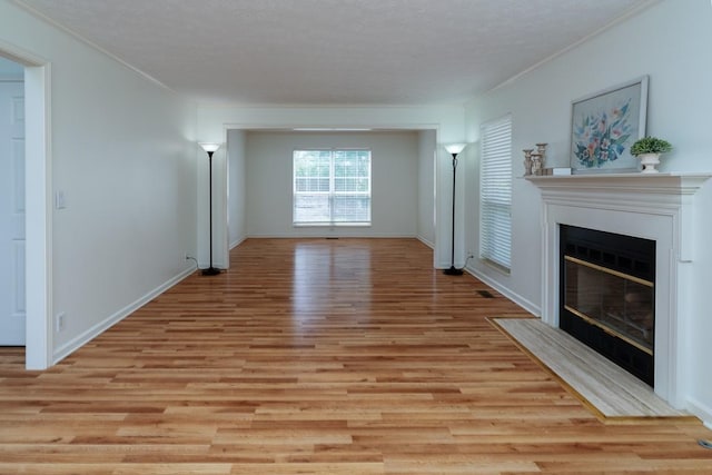 405 Parish Pl, Franklin, TN 37067 - unfurnished living room with light wood-style flooring, crown molding, a fireplace with flush hearth, baseboards, and a textured ceiling