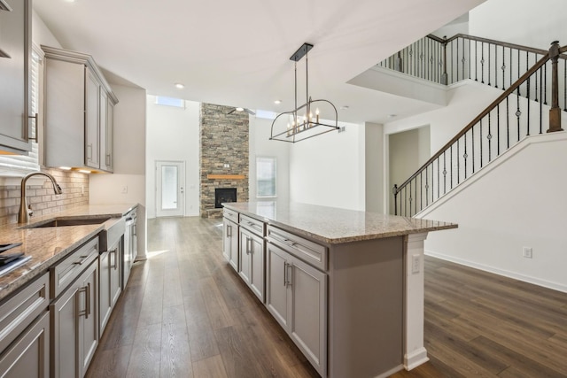 129 Willow Bend Dr, Mount Juliet, TN 37122 - kitchen featuring gray cabinetry, dark wood-type flooring, a sink, a fireplace, and decorative backsplash