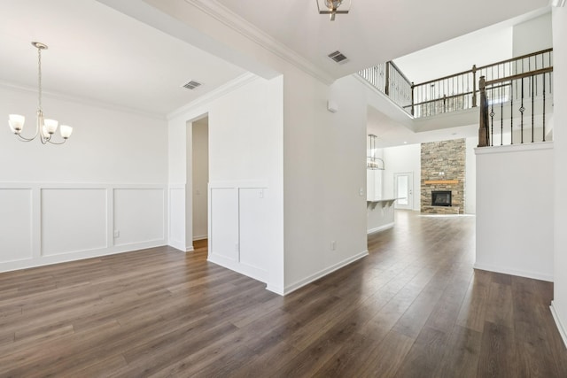 129 Willow Bend Dr, Mount Juliet, TN 37122 - unfurnished living room with a chandelier, dark wood-style floors, a decorative wall, a stone fireplace, and crown molding