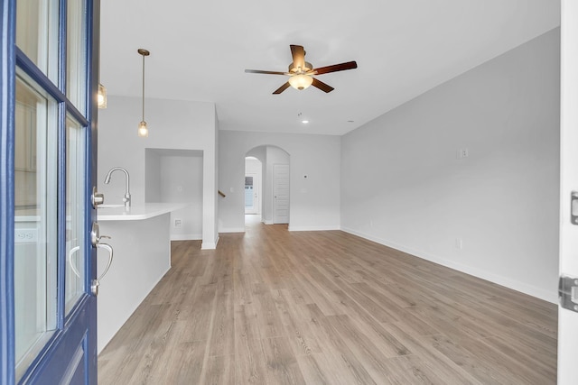 130 Beignet Aly, Hendersonville, TN 37075 - unfurnished living room with arched walkways, ceiling fan, light wood finished floors, a sink, and baseboards