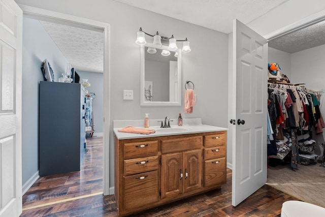 5024 Short Mountain Hwy, Smithville, TN 37166 - bathroom featuring a textured ceiling, vanity, wood finished floors, and a spacious closet