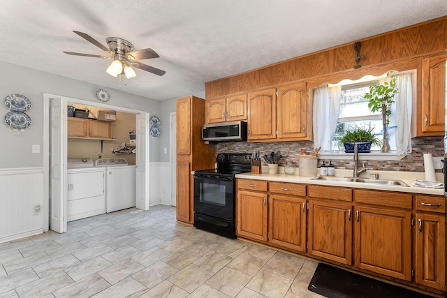 5024 Short Mountain Hwy, Smithville, TN 37166 - kitchen with black electric range, stainless steel microwave, a sink, independent washer and dryer, and brown cabinets
