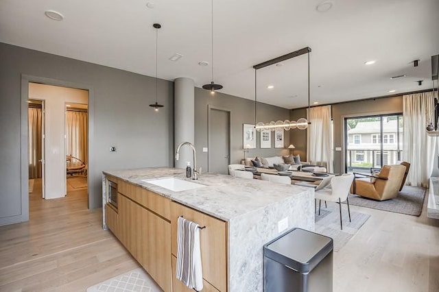 1030 17th Ave S Unit 201, Nashville, TN 37212 - kitchen with a sink, light wood-style floors, modern cabinets, light stone counters, and open floor plan