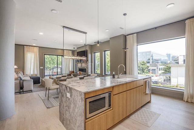 1030 17th Ave S Unit 201, Nashville, TN 37212 - kitchen featuring stainless steel microwave, a sink, modern cabinets, light wood-style floors, and a large island