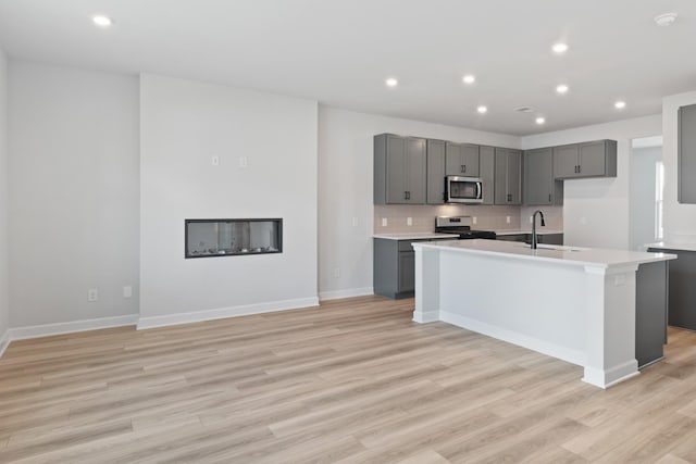 283 Subban Ct, Lebanon, TN 37087 - kitchen with appliances with stainless steel finishes, gray cabinets, light wood-style floors, a kitchen island with sink, and light countertops