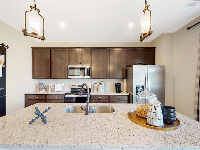 186 Millbrook Dr, Spring Hill, TN 37174 - kitchen featuring appliances with stainless steel finishes, a sink, dark brown cabinets, light stone counters, and hanging light fixtures