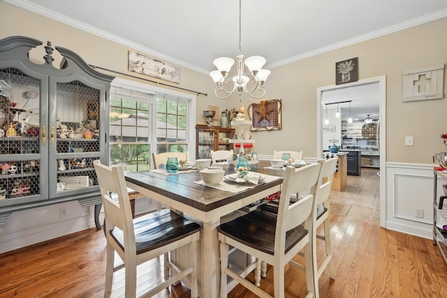 3198 Gray Hawk Ct, Clarksville, TN 37043 - dining area featuring crown molding, a chandelier, light wood-type flooring, and a wainscoted wall