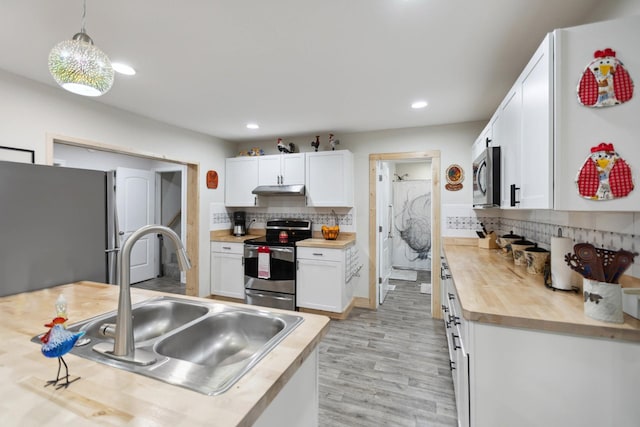 1602 Pleasant Grove Rd, Westmoreland, TN 37186 - kitchen featuring appliances with stainless steel finishes, wood counters, a sink, under cabinet range hood, and decorative backsplash
