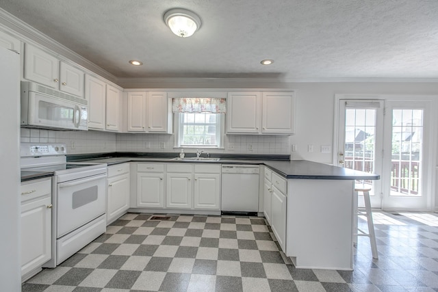 206 Sayre Ln, Murfreesboro, TN 37127 - kitchen with white appliances, a peninsula, crown molding, dark countertops, and white cabinets