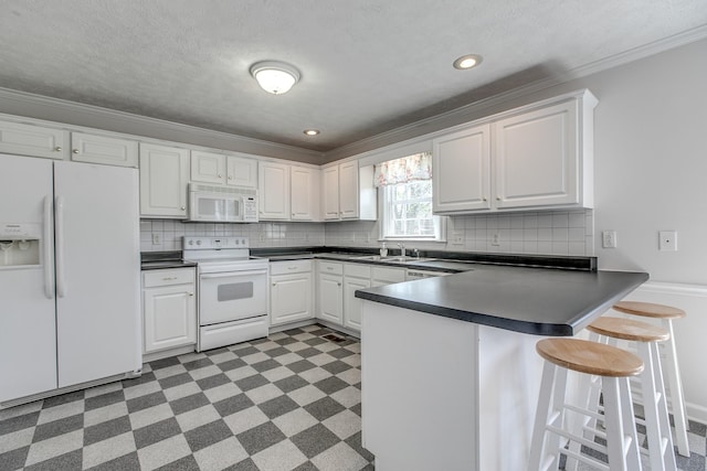 206 Sayre Ln, Murfreesboro, TN 37127 - kitchen with white appliances, ornamental molding, dark countertops, dark flooring, and a peninsula