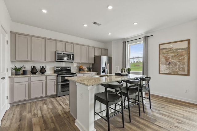 2502 Beverly Gail Rd, Pleasant View, TN 37146 - kitchen featuring appliances with stainless steel finishes, gray cabinets, an island with sink, light wood-style flooring, and recessed lighting