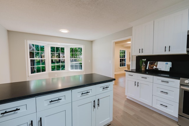 1405 SE Broad St, Murfreesboro, TN 37130 - kitchen featuring stainless steel range, light wood-style floors, dark countertops, white cabinets, and plenty of natural light