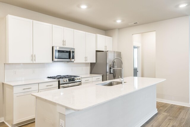 441 Golden Meadow Ln, Hendersonville, TN 37075 - kitchen featuring appliances with stainless steel finishes, light wood-style flooring, a kitchen island with sink, tasteful backsplash, and white cabinets
