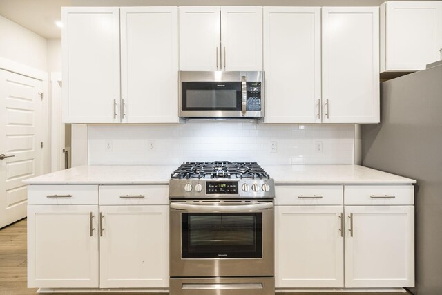 441 Golden Meadow Ln, Hendersonville, TN 37075 - kitchen with stainless steel appliances, white cabinets, backsplash, and light stone counters