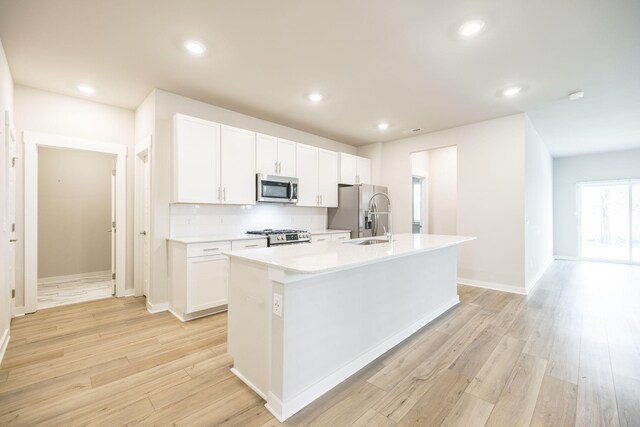 441 Golden Meadow Ln, Hendersonville, TN 37075 - kitchen featuring appliances with stainless steel finishes, a kitchen island with sink, tasteful backsplash, white cabinetry, and light wood-style flooring