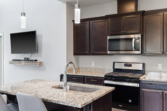 1339 Raden Dr, Lebanon, TN 37087 - kitchen featuring appliances with stainless steel finishes, a sink, dark brown cabinetry, decorative light fixtures, and a kitchen bar