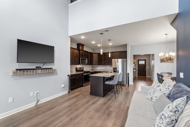 1339 Raden Dr, Lebanon, TN 37087 - kitchen featuring stainless steel appliances, dark brown cabinets, a breakfast bar, light wood-style flooring, and a chandelier