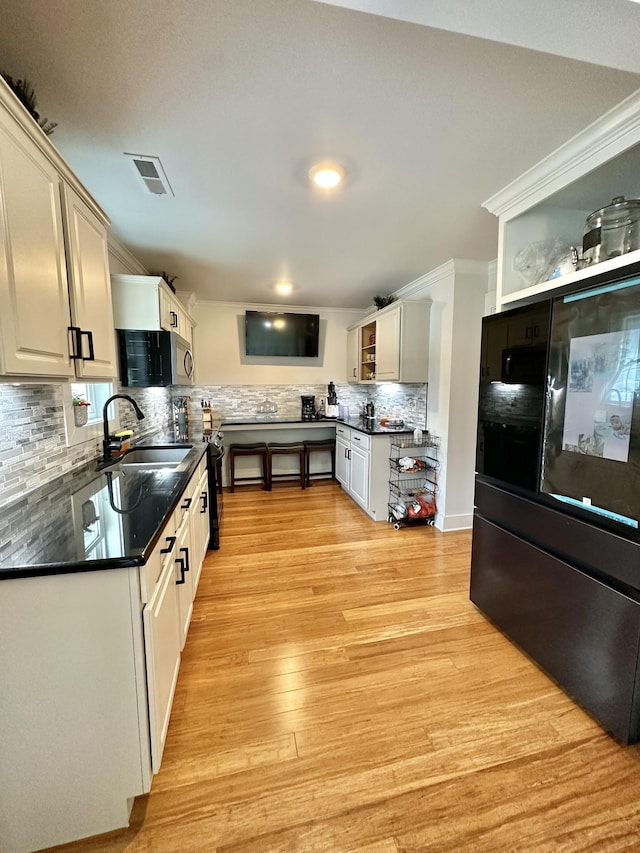 379 Thompson Ln, Tracy City, TN 37387 - kitchen with a sink, dark countertops, tasteful backsplash, light wood-style flooring, and stainless steel microwave