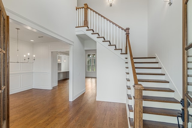 7100 Twelve Corners Rd, Lascassas, TN 37085 - stairway featuring wood finished floors, a chandelier, a towering ceiling, baseboards, and crown molding
