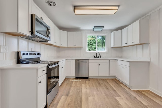 203 Summer St, Mount Pleasant, TN 38474 - kitchen featuring stainless steel appliances, light wood finished floors, a sink, light countertops, and white cabinets