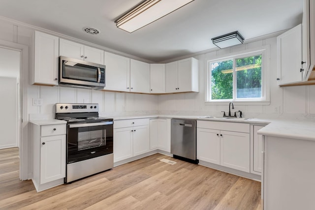 203 Summer St, Mount Pleasant, TN 38474 - kitchen featuring appliances with stainless steel finishes, a sink, light wood-style flooring, and white cabinetry