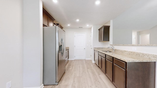 249 Edgefield Ct, Pleasant View, TN 37146 - kitchen with stainless steel appliances, dark brown cabinets, light wood-style floors, light stone countertops, and a peninsula