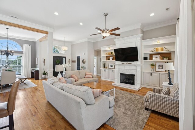 7579 Nightfall Cir, Ooltewah, TN 37363 - living area with a fireplace with raised hearth, a chandelier, ornamental molding, light wood-style floors, and ceiling fan