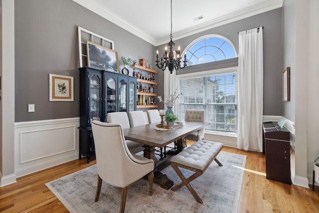 7579 Nightfall Cir, Ooltewah, TN 37363 - dining room featuring a chandelier, light wood-type flooring, crown molding, and a wainscoted wall