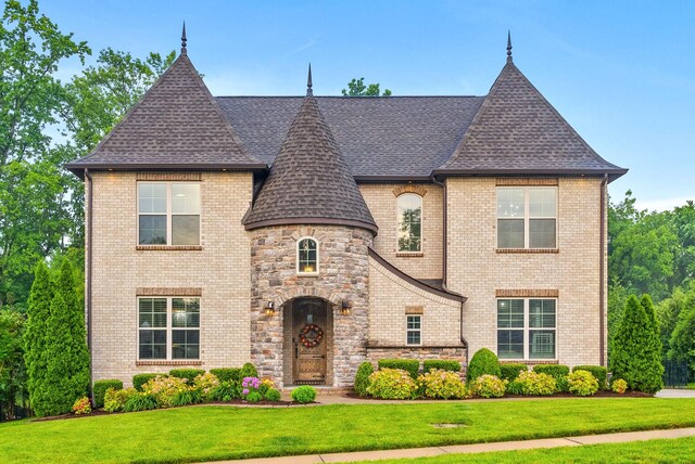 127 Copperstone Dr, Clarksville, TN 37043 - french country home featuring a shingled roof, a front lawn, brick siding, and stone siding