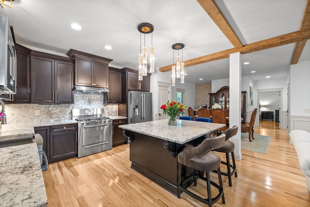 127 Copperstone Dr, Clarksville, TN 37043 - kitchen with stainless steel appliances, dark brown cabinets, under cabinet range hood, light stone counters, and a kitchen breakfast bar