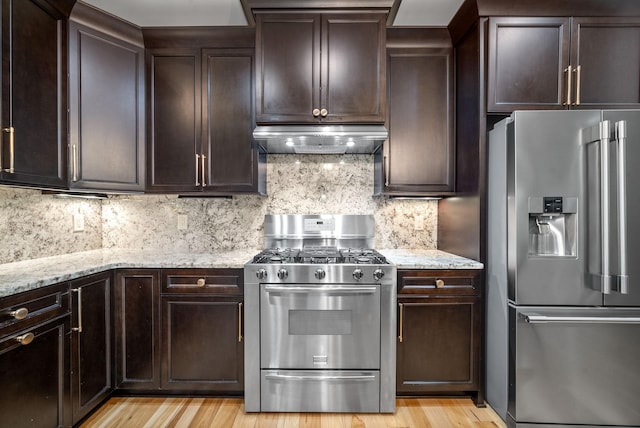 127 Copperstone Dr, Clarksville, TN 37043 - kitchen with stainless steel appliances, under cabinet range hood, light stone countertops, dark brown cabinetry, and light wood-style floors