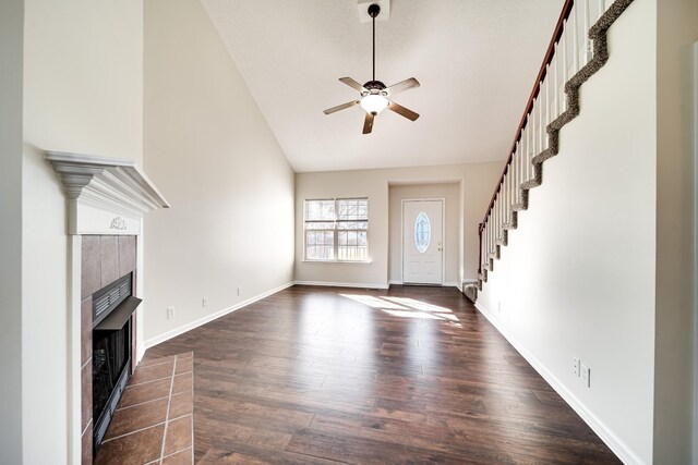 3889 Mackenzie Dr, Clarksville, TN 37042 - unfurnished living room featuring a tile fireplace, ceiling fan, dark wood-style flooring, stairway, and baseboards
