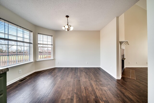 3889 Mackenzie Dr, Clarksville, TN 37042 - empty room with a chandelier, a textured ceiling, dark wood finished floors, baseboards, and a fireplace with flush hearth