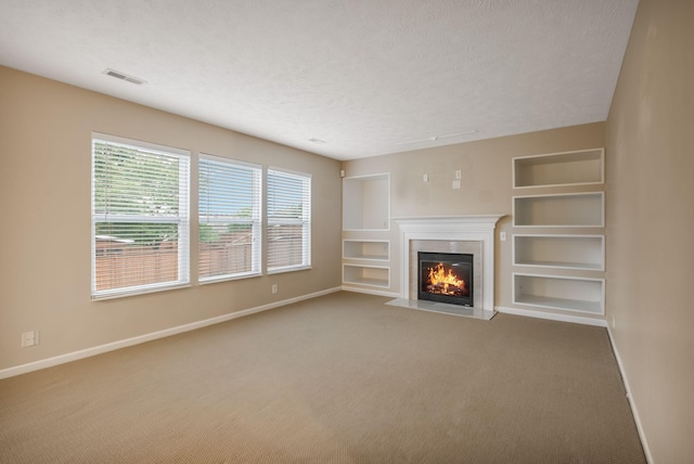 905 Arbor Springs Dr, Mount Juliet, TN 37122 - unfurnished living room featuring baseboards, carpet flooring, a glass covered fireplace, built in features, and a textured ceiling