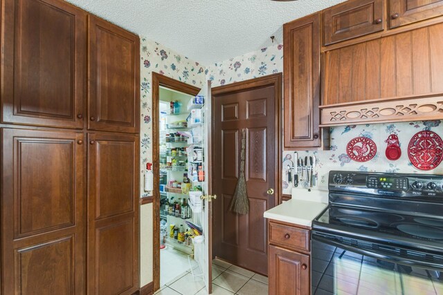 2119 W Lincoln St, Tullahoma, TN 37388 - kitchen featuring wallpapered walls, black electric range, light tile patterned flooring, light countertops, and a textured ceiling