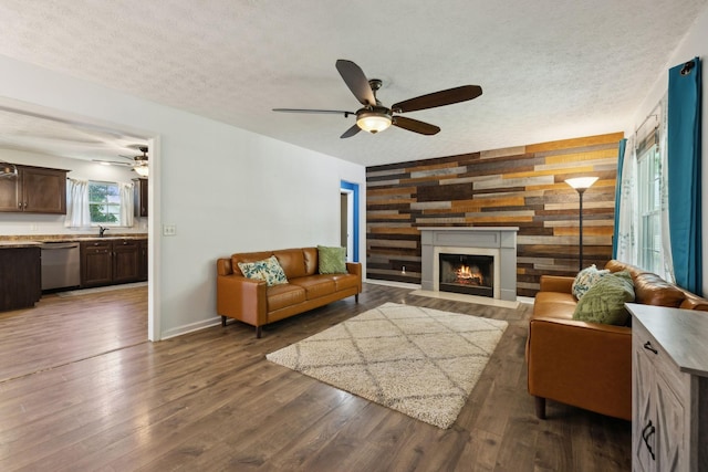 4010 Swift Springs Ct, Goodlettsville, TN 37072 - living room featuring an accent wall, a ceiling fan, wooden walls, a warm lit fireplace, and a textured ceiling