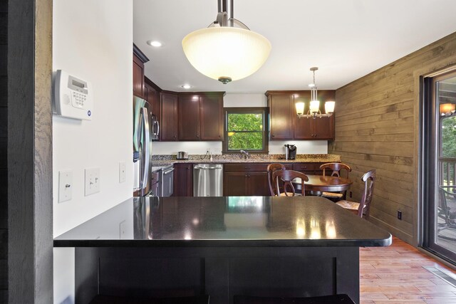 100 Acree Ln, Estill Springs, TN 37330 - kitchen with appliances with stainless steel finishes, a peninsula, wooden walls, a sink, and light wood-style floors