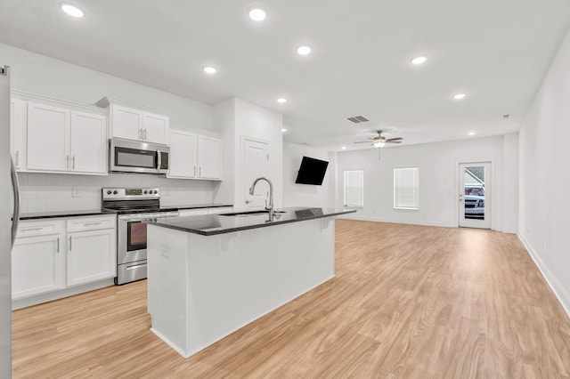 923 SE Broad St Unit A4, Murfreesboro, TN 37130 - kitchen featuring appliances with stainless steel finishes, dark countertops, a ceiling fan, white cabinetry, and light wood-type flooring