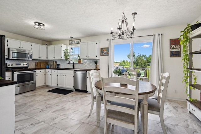 8635 Pleasant Hill Rd, Cross Plains, TN 37049 - kitchen with stainless steel appliances, light marble finish floors, dark countertops, a chandelier, and tasteful backsplash