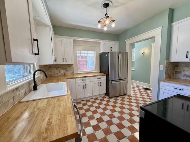 425 Arlington Ave, Jackson, TN 38301 - kitchen with freestanding refrigerator, a sink, wood counters, black range with electric stovetop, and white cabinetry