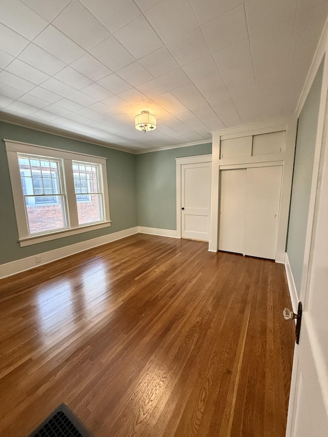 425 Arlington Ave, Jackson, TN 38301 - unfurnished bedroom featuring crown molding, dark wood-style flooring, a closet, and baseboards