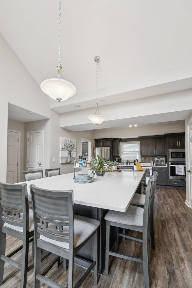 803 Bradford Pl, Murfreesboro, TN 37130 - kitchen featuring dark brown cabinetry, dark wood finished floors, light countertops, a kitchen bar, and vaulted ceiling